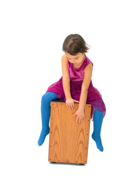 Küçük kız beyaz arka plan üzerinde izole bir cajon ile oynarken
