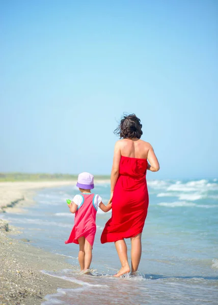 Achteraanzicht van een moeder met haar kleine meisje wandelen aan de kust — Stockfoto