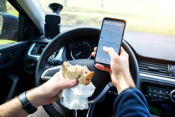 man eating and texting while driving car