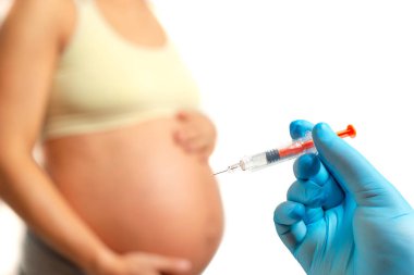 Doktor el, beyaz arka planda izole edilmiş hamile kadının karnına pıhtılaşma önleyici enjekte etmeye hazırlanıyor.