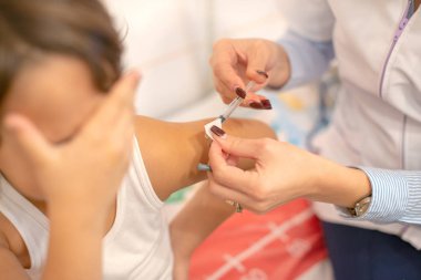 Bakmaya korkan küçük bir kıza şırıngayla insan eli enjekte edilirken. Seçici odak