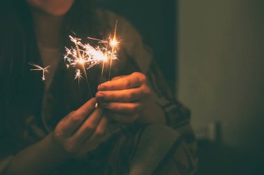 Genç bayan merdivenlerde oturuyor, elinde ışıltı var.