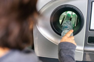 Geri dönüşüm makinesindeki kadın plastik şişeleri geri dönüştürüyor, ekoloji konsepti