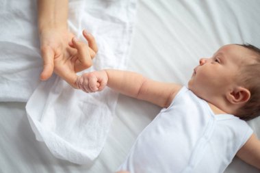 Yeni doğmuş bir bebek yatağa uzandığında annesinin parmağını tutar..