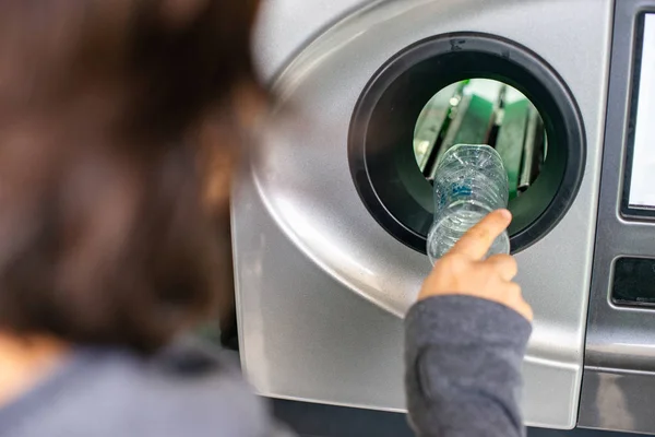 Geri dönüşüm makinesindeki kadın plastik şişeleri geri dönüştürüyor, ekoloji konsepti