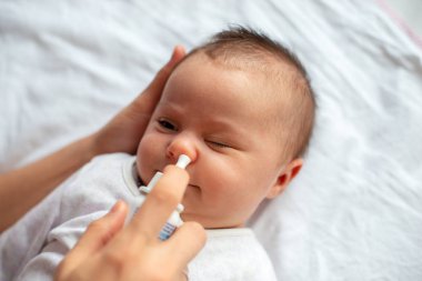 Woman using nasal spray for baby clipart