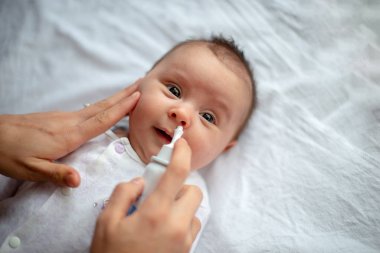 Woman using nasal spray for baby clipart