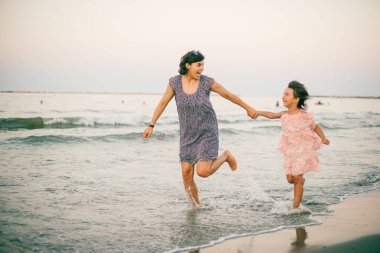 Anne ve kızı kumsalda güneşlenirken birlikte eğleniyorlar.