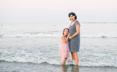 Anne ve kızı kumsalda güneşlenirken birlikte eğleniyorlar.