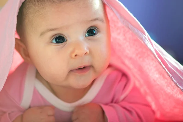 かわいい3ヶ月赤ちゃんの女の子幼児ベッドの上で彼女の大きな目でカメラを見上げ頭で彼女の腹に 天然の寝室の光 — ストック写真