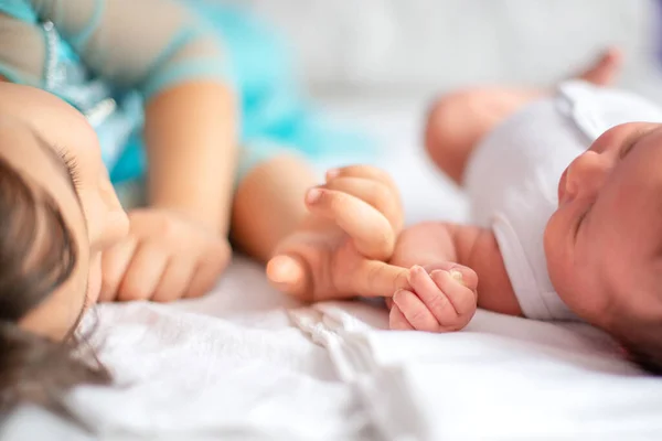 新生児と姉は手を取り合ってベッドの上で — ストック写真