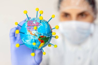 Koronavirüs salgını, elinde Coronavirüs şeklinde bir dünya küresi tutan kadın bilim adamı.