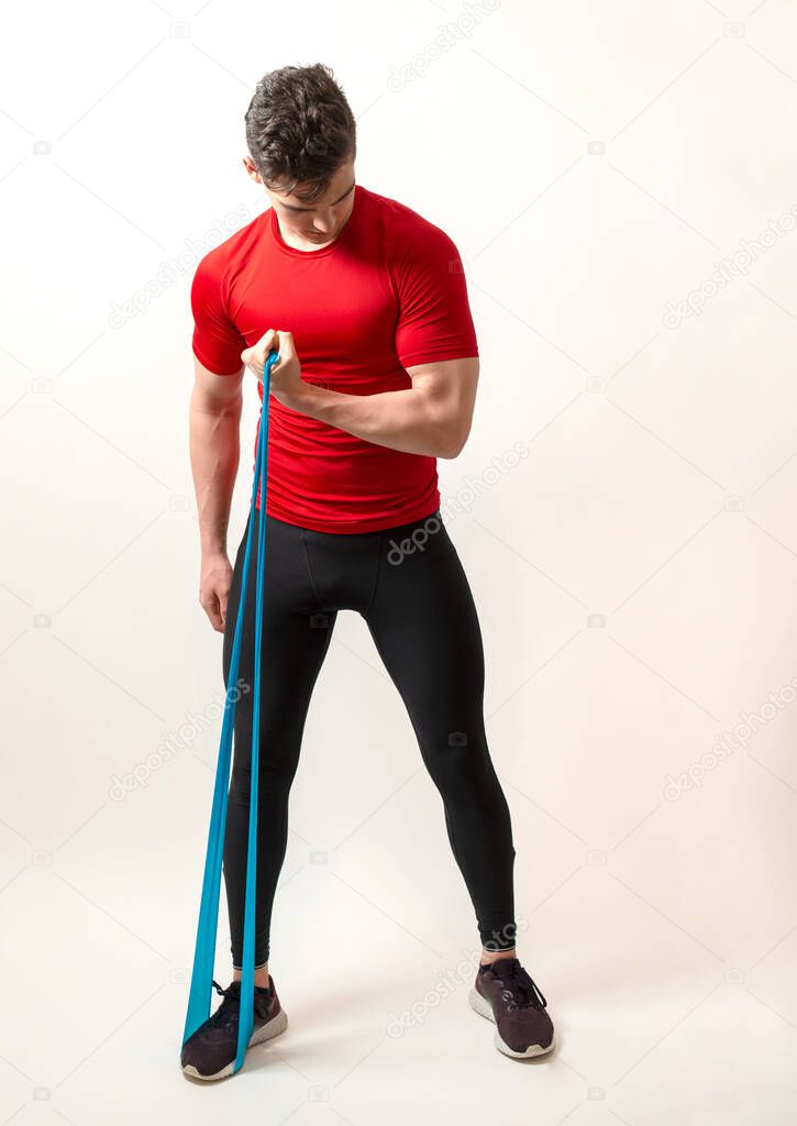 Young athlete isolated on white background stretches a sports elastic band