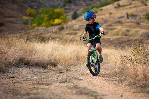 快乐的7岁男孩在秋天的公园里玩着自行车在美丽的秋天 活泼的孩子穿着自行车头盔 — 图库照片