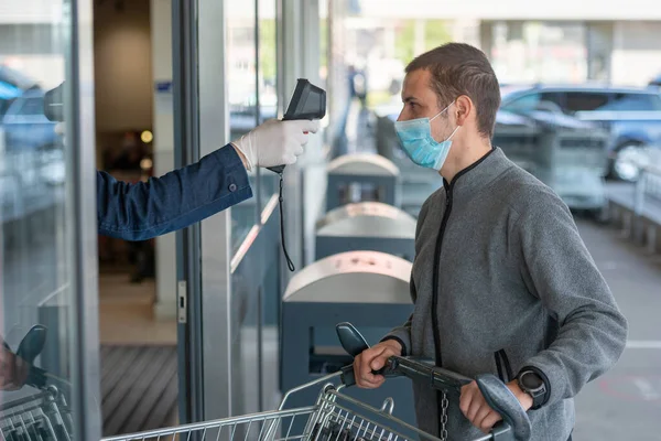 Temperature check at a supermarket of man, grocery store with thermal imaging camera. Image monitoring scanner to monitor the body temp of visitor customer