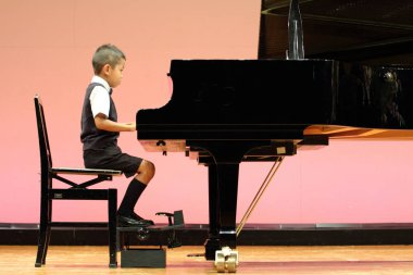 Japanese boy playing a piano (first grade at elementary school) clipart