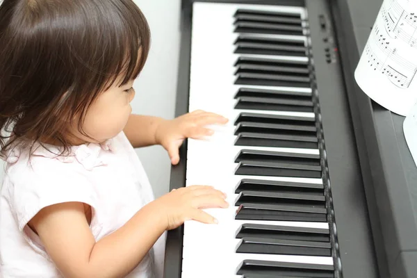 Japansk jente spiller piano (1 år gammel) ) – stockfoto