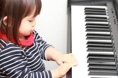 Japanese girl playing a piano (2 years old) clipart