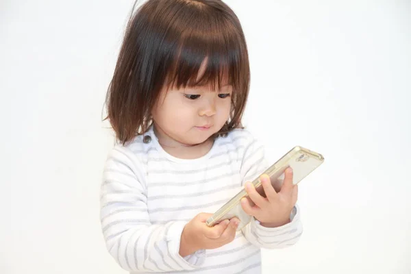 使用智能手机 （2 岁的日本女孩) — 图库照片