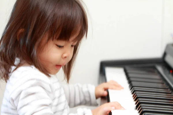 Japansk jente spiller piano (2 år gammel) ) – stockfoto