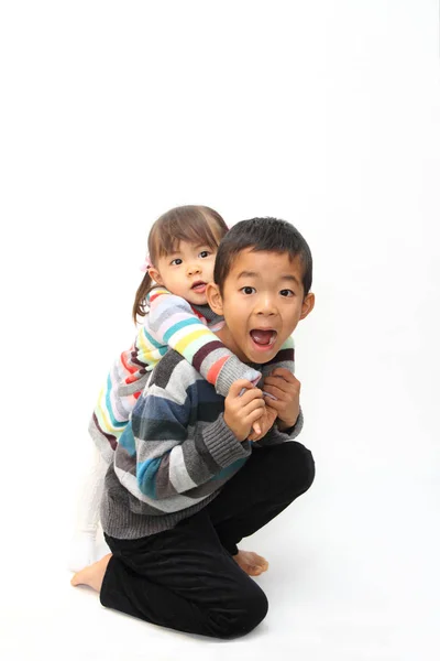 그의 뒤 (7 살 소년과 2 년 오래 된 여자에 그의 자매를 들고 일본 소년) — 스톡 사진
