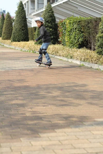 Japonés chico cabalgando en un casterboard (primer grado en la escuela primaria ) — Foto de Stock