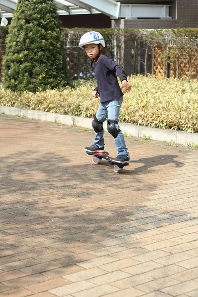 日本男孩骑着 casterboard （就读小学一年级) — 图库照片