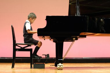 Japanese boy playing a piano (first grade at elementary school) clipart
