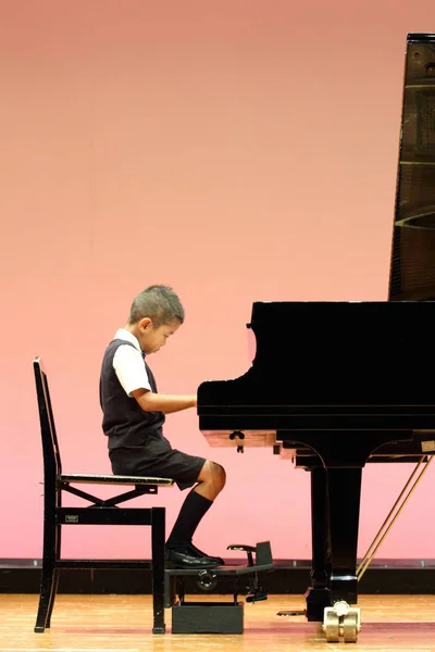 Japansk pojke spela piano (första klass i grundskolan) — Stockfoto