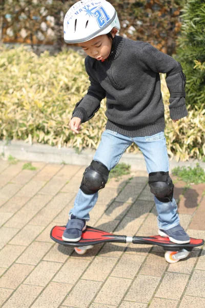 Японський хлопець їзда на casterboard (перший сорт в початковій школі) — стокове фото