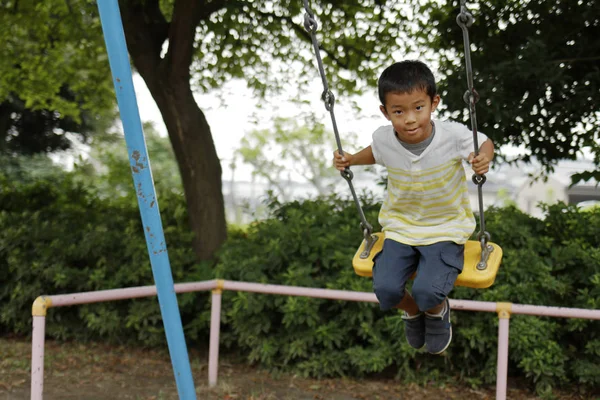 ブランコに乗っている日本少年 (小学校 2 年生) — ストック写真