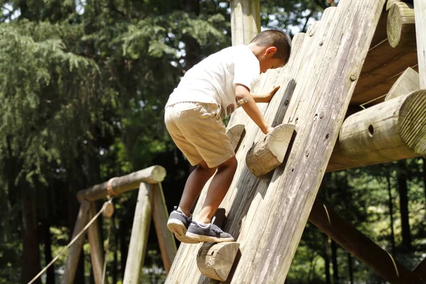 Japanischer Junge klettert an der Wand (zweite Klasse der Grundschule)) — Stockfoto