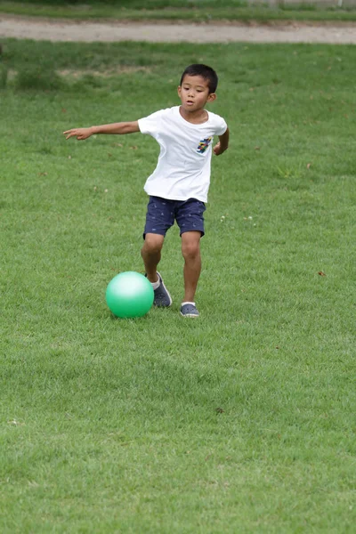 Japanese boy playing with soccer ball (second grade at elementary school)