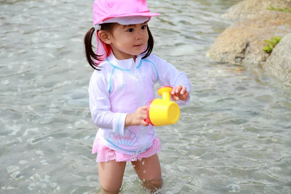 Japansk flicka som leker med vatten med långtidsvattnande kruka (2 år gammal) — Stockfoto