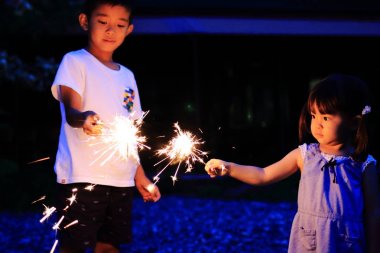 Japon kardeşi ve kız kardeşi el havai fişek (7 yaşında çocuk ve 2 yıl yaşlı kız yapıyor)