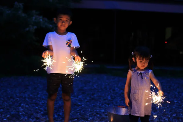 Kakak beradik Jepang yang sedang membuat kembang api genggam (7 tahun anak laki-laki dan 2 tahun perempuan ) — Stok Foto