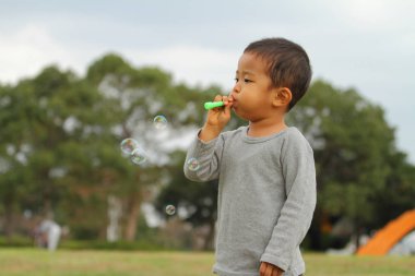 Japon çocuk iskambil kabarcık (3 yaşında) çim ile