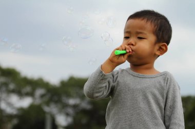 Japon çocuk iskambil kabarcık (3 yaşında) çim ile