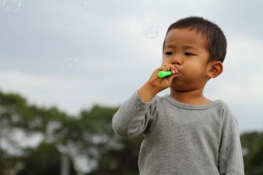 Japon çocuk iskambil kabarcık (3 yaşında) çim ile