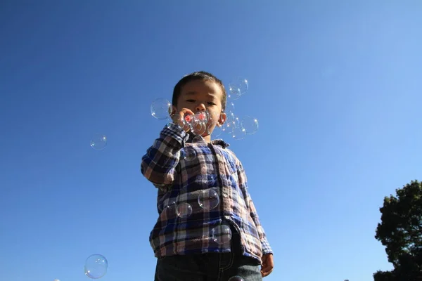 Japansk pojke leker med bubbla (3 år) på gräset — Stockfoto