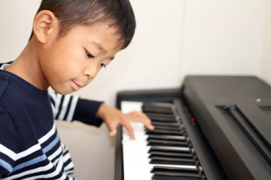 Japanese boy playing a piano (second grade at elementary school) clipart