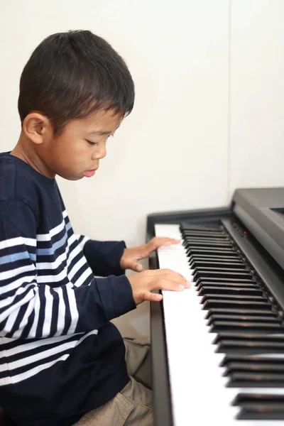 Japanese boy playing a piano (second grade at elementary school) — Stock Photo, Image