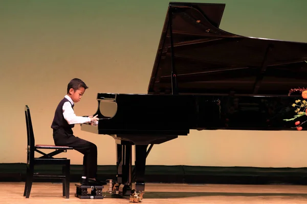 Japansk pojke spela piano på scenen (årskurs i grundskolan) — Stockfoto