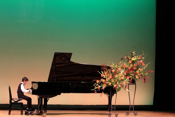 Japansk pojke spela piano på scenen (årskurs i grundskolan) — Stockfoto