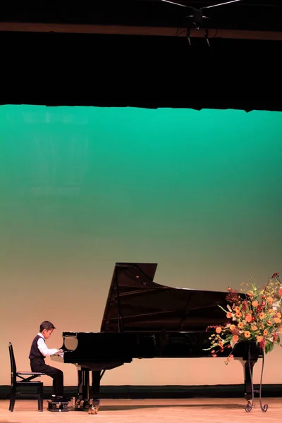 Japonês menino tocando piano no palco (segunda série na escola primária ) — Fotografia de Stock