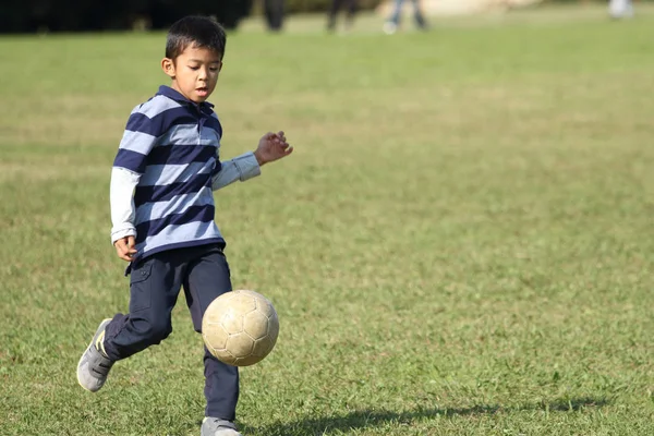 サッカー ボールで遊ぶ日本人の少年 (小学校 2 年生) — ストック写真