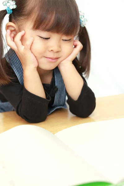 Japon kız elleri (3 yaşında çenesi ile bir resim kitap okuma) — Stok fotoğraf