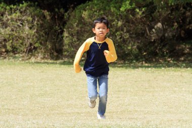 Japon çocuk çimenlerin üzerinde çalışan (üçüncü sınıf ilköğretim okulunda)