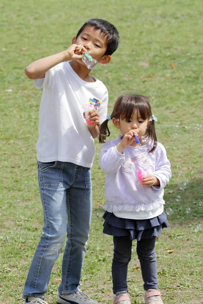 日本の兄と妹 (8 歳の男の子と 3 年古い女の子のバブルで遊んで) — ストック写真