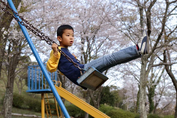 ブランコに乗っている日本少年 (小学校 3 年生) — ストック写真